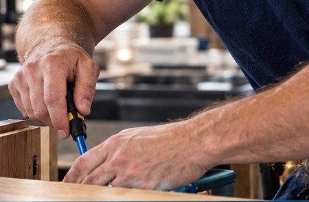 Hands tightening a fixture on a wooden cabinet